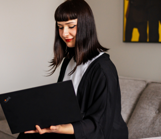 A 7N staff member working on her computer while sitting on the sofa
